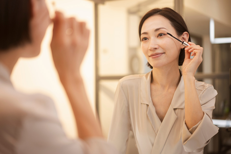 鏡を見ながらマスカラを塗っている女性