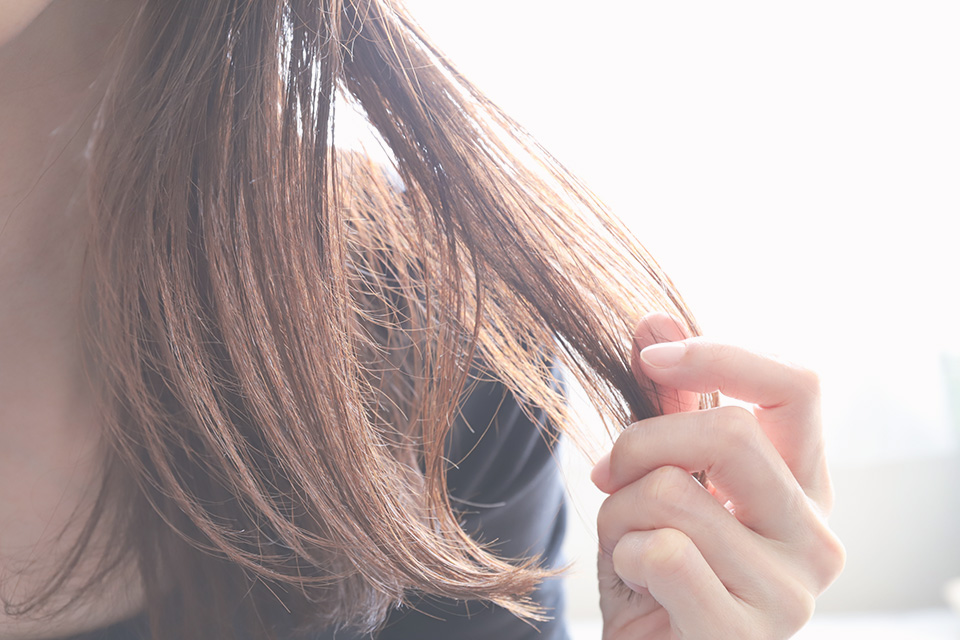 傷んだ髪の毛を触る女性